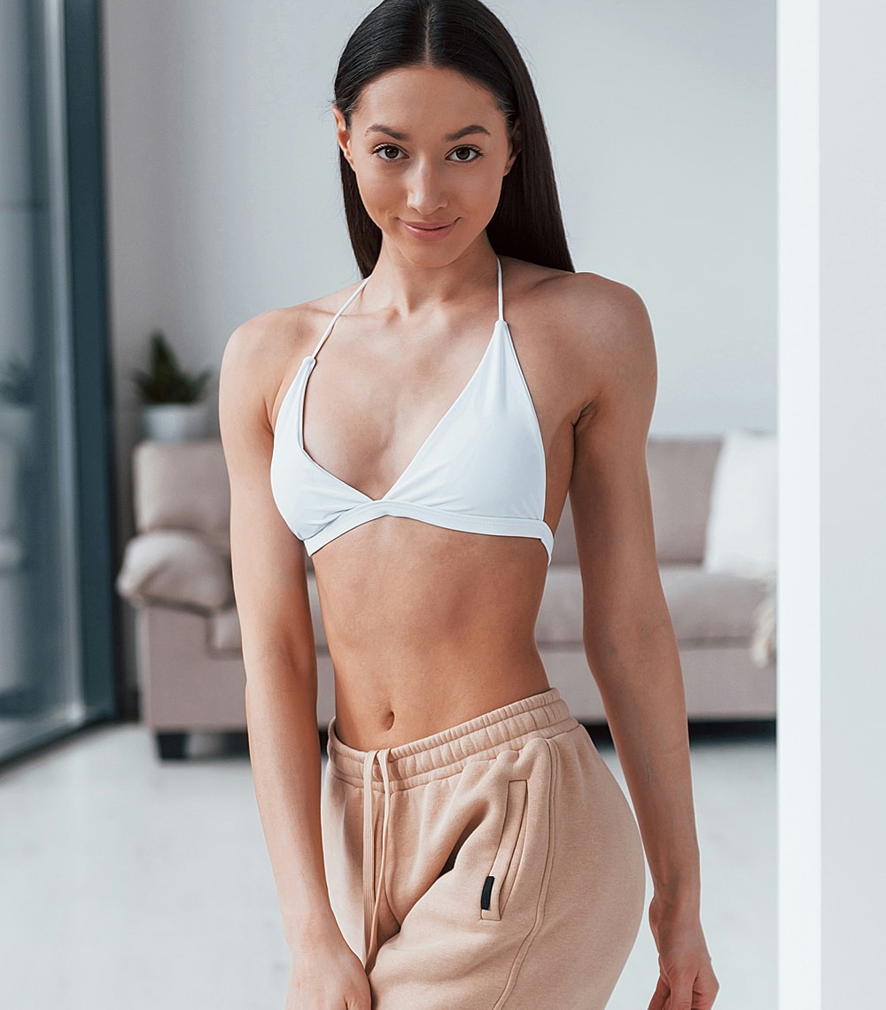 Woman in white bikini and casual pants.